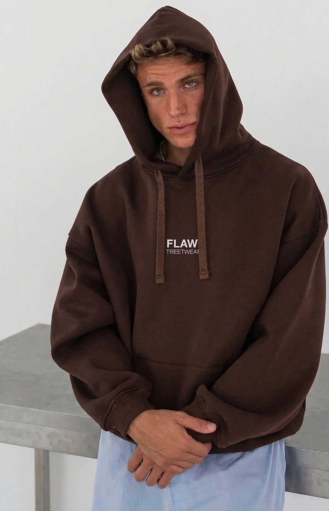 Modelo usando polerón canguro oversized café FLAW con logo frontal